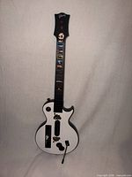 Full front view of white and black Gibson-branded Guitar Hero controller