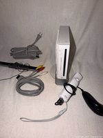 Front view of Wii console on stand with remote, Nunchuk, cables