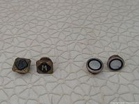 Two pairs of cuff links side by side on textured surface showing front face detail