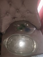 Two vintage glass platters displayed on a beige tufted chair, showing overall shape and size comparison.