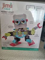Front of the box showing the assembled Meebot robot with LED eyes, servo motors, gear system, and colorful components. Brand and product information clearly visible.