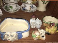 Photo showing four vintage ceramic planters including a dog-shaped planter, a Wade figurine, and other items on a shelf.