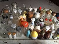 Wide view of 58 assorted salt and pepper shakers on a surface, showcasing different materials and styles