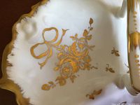 Close-up of the gold bow and rose hand-painted design detailing on the white porcelain dish.