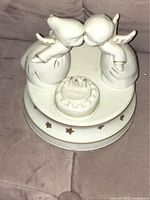 Front view of the music box showing the two angel figurines leaning over the birthday cake.
