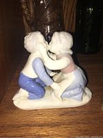 Front view of porcelain figurine showing two children in pastel clothes kissing