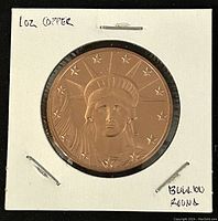 Obverse side of 1 oz Copper Round featuring Liberty Head design in a white holder with handwritten '1oz Copper' and 'Bullion Round'.