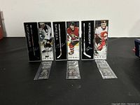 Photo of the three mini hockey sticks in their display cases side by side showing Lecavalier, Spezza, and Kiprusoff