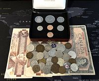 Overview of all items showing banknotes and assortment of coins including a boxed coin set.