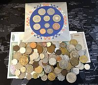 Photo showing the 2005 UNC coin set arranged on a card with 10 coins and the scattered assortment of 75+ additional coins and 8 banknotes beneath.