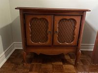 Front view of brown wooden cabinet with two doors featuring lattice panels and rounded edges.