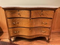 Full frontal view of oak dresser; shows four serpentine front drawers with brass pulls and marble top
