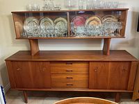 Full front view of credenza base and glass hutch loaded with glassware (contents not included)