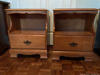 Pair of wooden bedside cabinets next to each other on parquet floor, showing front view.