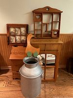 Overall lot including wooden decorative shelf with heart cutouts, vintage aluminum milk can with handles, and other wooden items in background.
