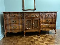 Front view of the wooden vintage dresser showing the carved floral details, drawers, and cabinet doors with lattice design.