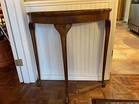 Front view of the wooden semi-circular hall table with cabriole legs showing its shape and finish.