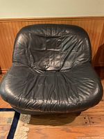 Front view of navy blue leather swivel chair showing stitched square pattern and seated cushion with wear creases.
