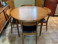 Front view of round teak dining table with four chairs around