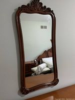 Front view of the large wall mirror showing the detailed carved wooden frame and reflection in the glass.
