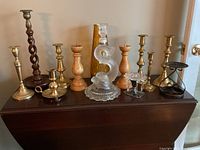 Overview of twelve candle holders arranged on a dark wooden surface showing variety of materials.