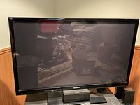 Samsung 43-inch flat-screen TV powered on, showing a black screen with reflection and light dust on screen and edges.