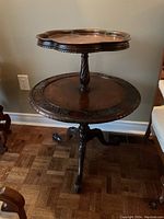 Full view of two-tier wooden table showing carved pedestal and claw feet.