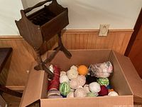 Wooden yarn stand next to a box containing multiple yarn balls in various colors.