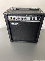 Front view of Rocker RX-100 guitar amplifier showing control panel and brand logo.