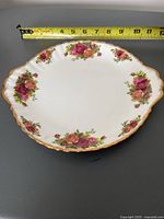 Top view of Royal Albert Old Country Roses serving plate showing floral design and gold trim with measuring tape approx. 12 inches wide.