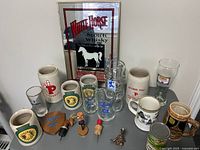 Wide view of the collection including ceramic mugs, glassware, bottle stoppers, and framed bar sign