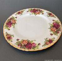 Single salad plate showing floral rose pattern with gold trim on white bone china.