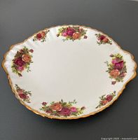 Top-down view of an oval serving plate with floral rose clusters and gold rim