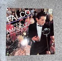 The front cover of the vinyl record showing Falco in a tuxedo with vintage microphone and ornate audience background.