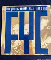Front view of vinyl record sleeve for Fine Young Cannibals single 'Suspicious Minds' featuring the band photo with large blue letters 'FYC'