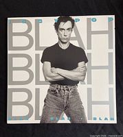 Front cover of Iggy Pop 'Blah Blah Blah' vinyl album showing black and white portrait of artist with hands crossed, title in large block letters
