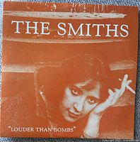 Front album cover of The Smiths Louder Than Bombs vinyl double album showing orange cover with woman smoking and album title.