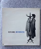 Vinyl LP record sleeve with coat rack and coat/hat image and text "The Style Council Come to Milton Keynes"