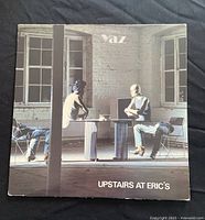 Front cover of the vinyl album 'Upstairs at Eric's' by Yaz showing two people sitting at a table in a rustic room.