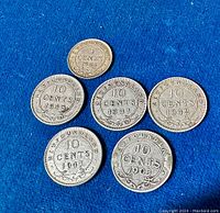 Six Newfoundland silver coins arranged on blue felt background showing front with dates and denominations visible. Coins show 5 cent and 10 cent values and date range from 1903 to 1947.
