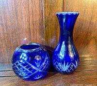 Photo showing both vases side by side on wooden surface showcasing their shape and color contrast.