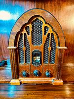 Front view of the cathedral style General Electric radio showing wood casing, speaker grille with Gothic arch design, tuning dial, and control knobs.