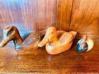 Three vintage wooden duck decoys together, showing size differences and wood grain