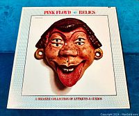 Front cover close-up of Pink Floyd Relics vinyl record showing sculpted face mask artwork with tongue out on a white background.