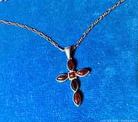 Close-up of the crucifix pendant showing amber cabochon stones set in sterling silver on blue background.