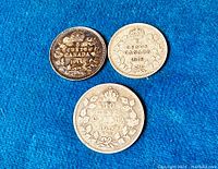 Coins laid out showing reverse side with denominations 5 Cents 1914, 5 Cents 1919, 10 Cents 1919 and maple leaf wreath
