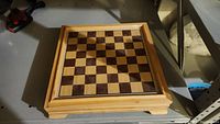 Top view of closed wooden game box showing a chess and checkers board surface.