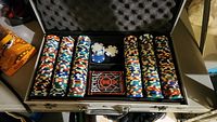 Top-down view of poker set in open aluminum carry case showing poker chips, loose chips, and Bicycle playing cards.