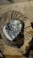 Photo showing brown storage bag containing folded silver/gray inflatable mattress.