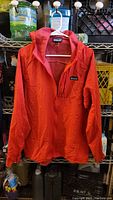 Front view of red Patagonia jacket hanging on white hanger showing zipper and collar details.